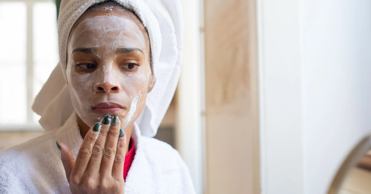 Femme appliquant de la crème pour le visage dans la salle de bain, partie de sa routine quotidienne de soins de la peau.