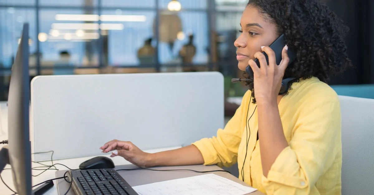 Une jeune femme travaillant dans un environnement de centre d'appels moderne, engageant une conversation via un casque.