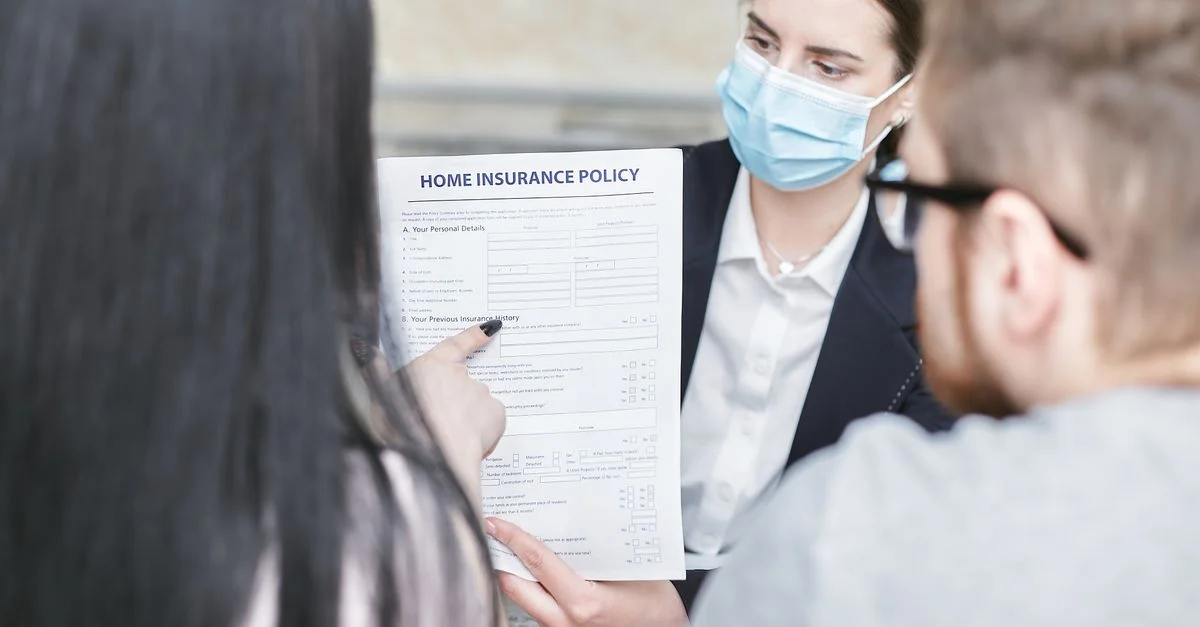 Une femme professionnelle explique une police d'assurance habitation à des clients lors d'une réunion. Cadre intérieur.