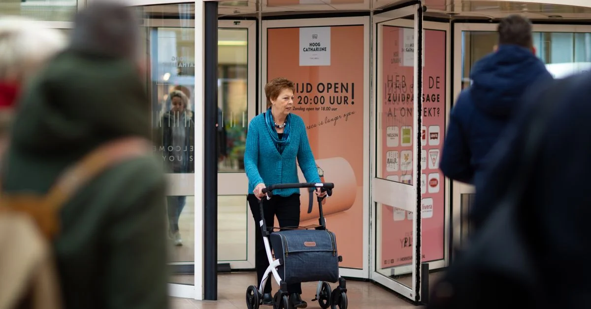 Femme âgée utilisant un déambulateur dans un centre commercial à Utrecht, capturée de manière candide.