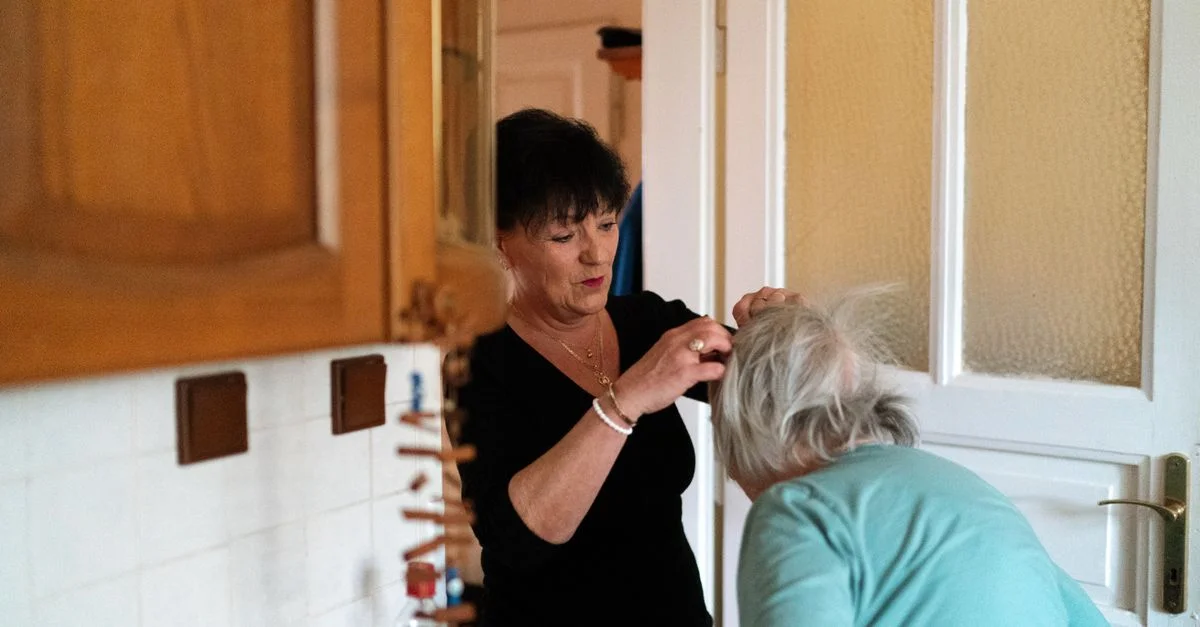 Une aide-soignante aide une femme âgée à faire sa toilette dans un environnement familial chaleureux.