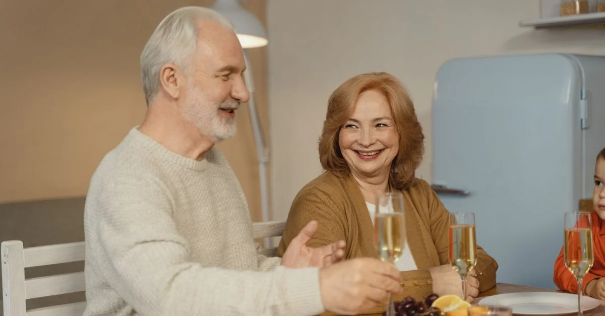 Un couple âgé profitant d'un dîner familial joyeux avec du champagne et des fruits.
