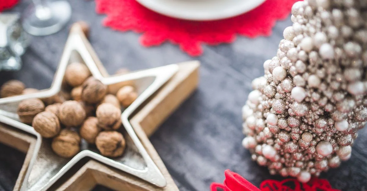 Gros plan d'une table de Noël festive avec un plateau en étoile, des noix et des décorations.