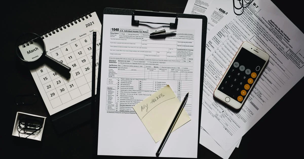 Vue en plongée de formulaires fiscaux, calculatrice, calendrier et stylo pour la planification financière.