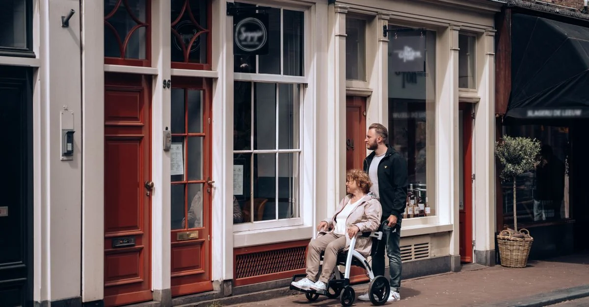 Un homme aide une femme en fauteuil roulant dans une rue pittoresque à Amsterdam, aux Pays-Bas.