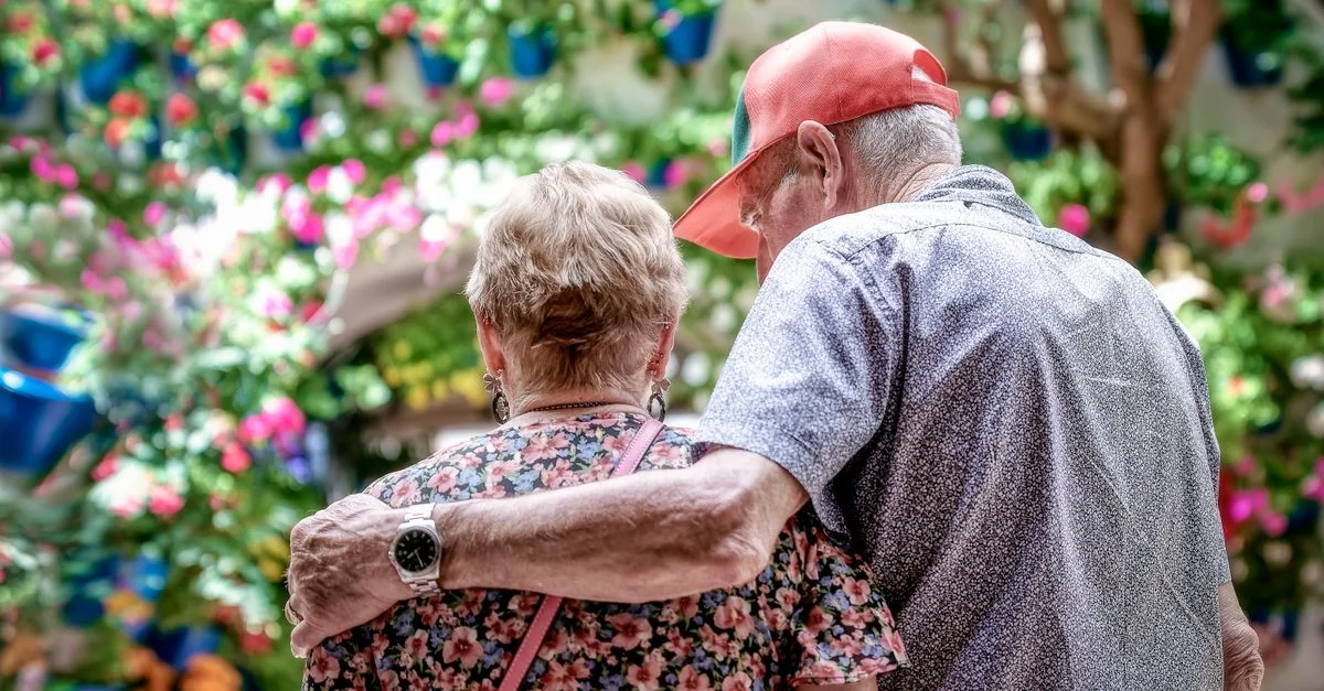 Un couple senior aimant s'enlace en plein air dans un jardin coloré à Córdoba, Espagne.
