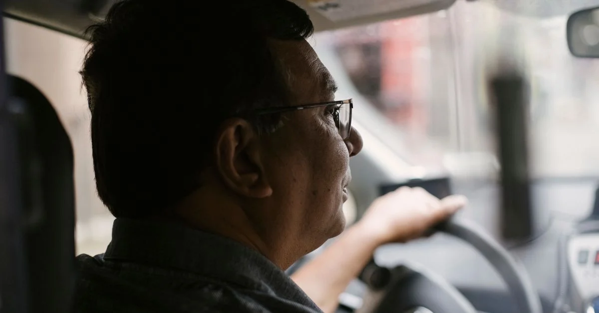 Homme senior conduisant dans une zone urbaine, concentré sur la route devant lui.